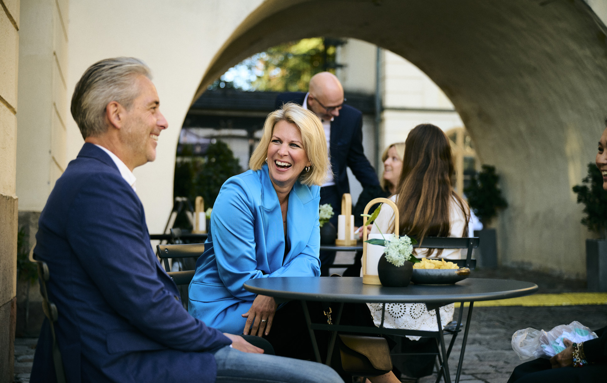 Glada kollegor klädda i olika nyanser av blått på en solig innergård