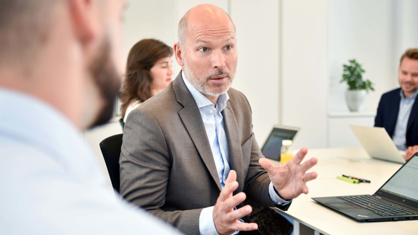 Thomas Lindahl från Zington sitter vid ett bord med andra medarbetare och gestikulerar medan han pratar.