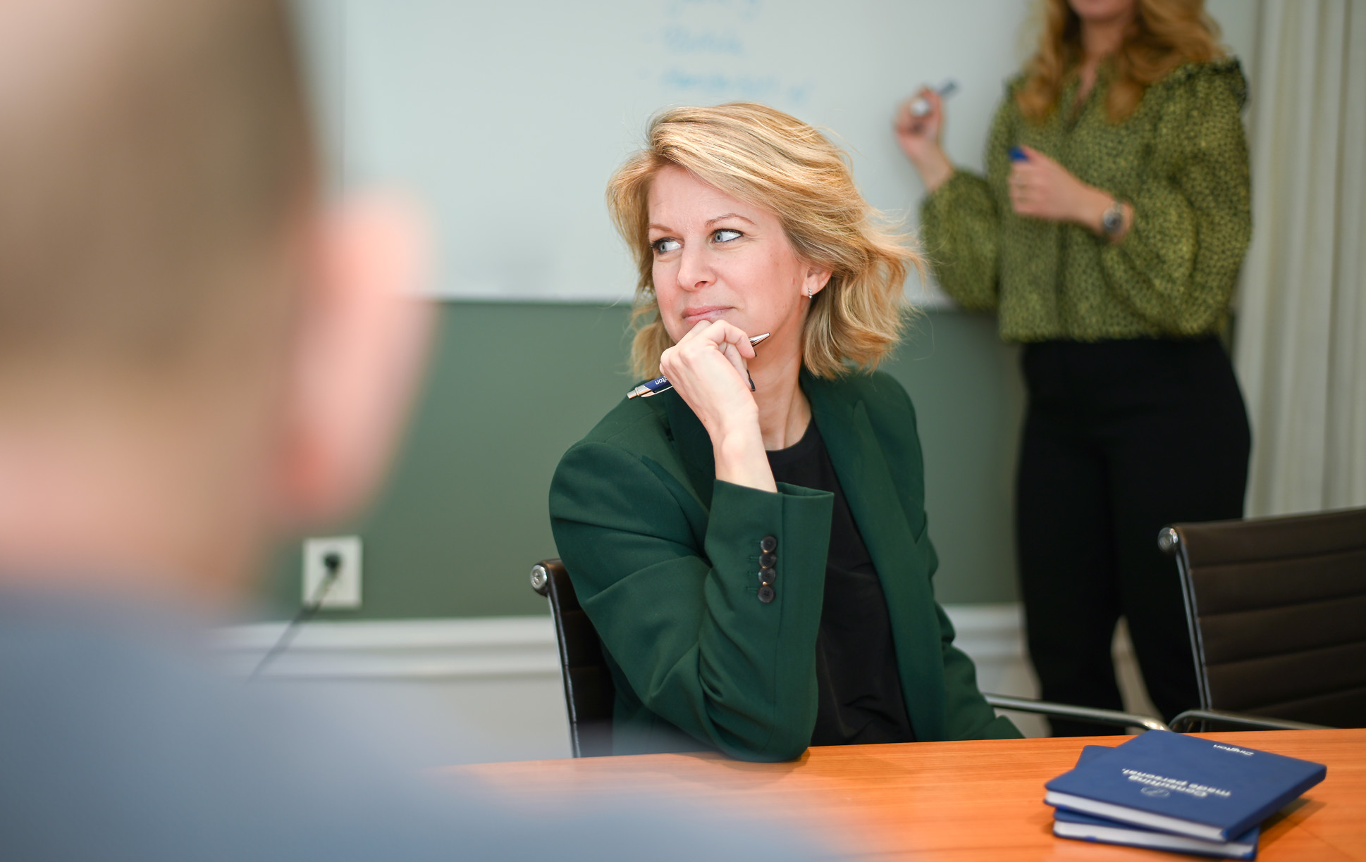 En kvinna som sitter vid ett bord och ser fundersam ut.