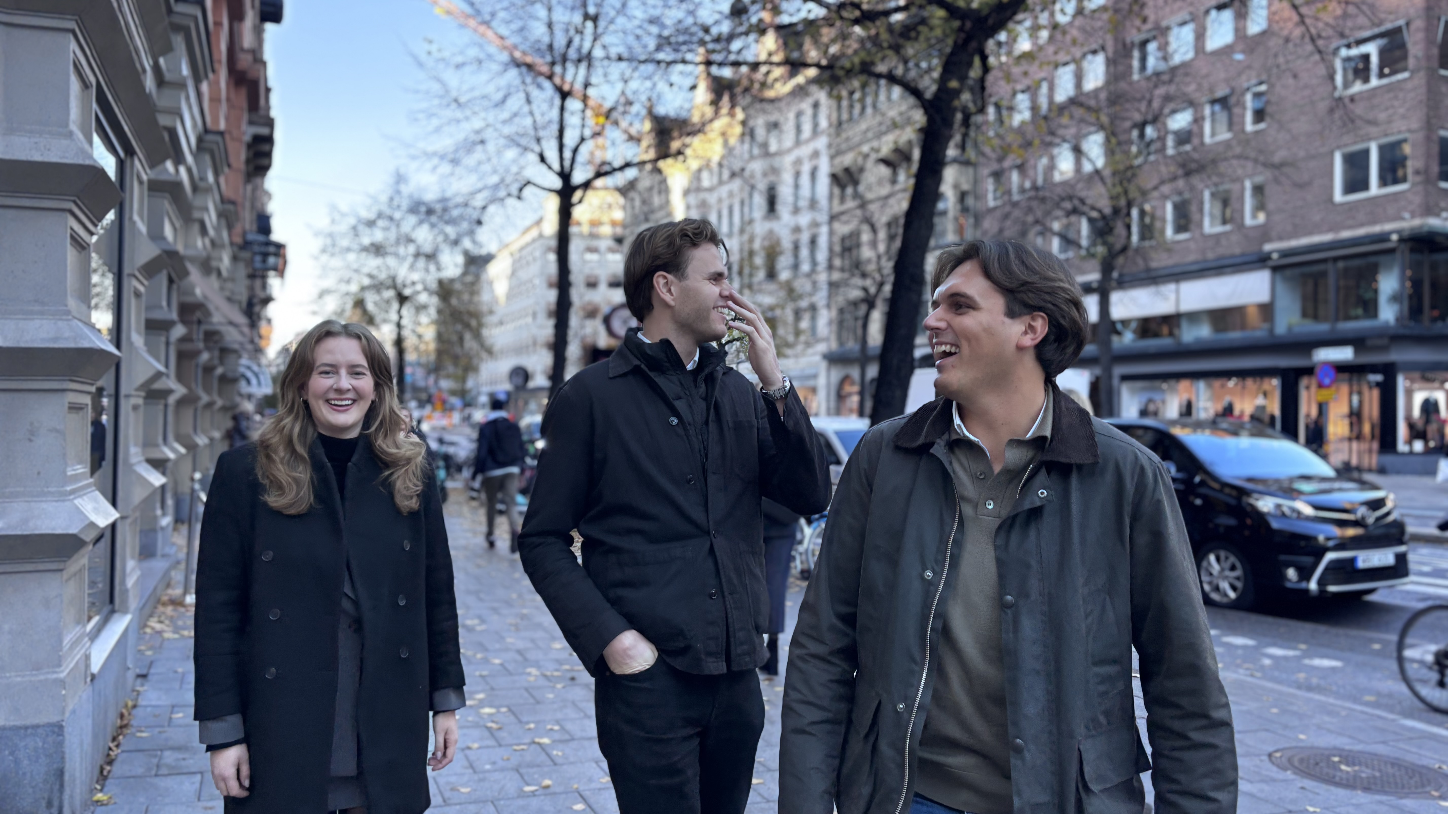 En bild på tre människor som går utomhus på en gata.