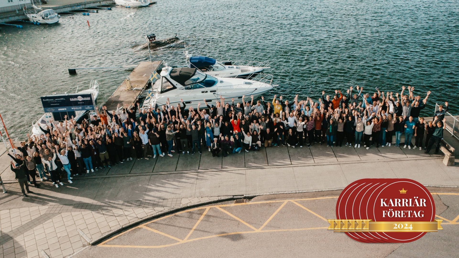 En överbild på en massa människor som står på en kaj med motor båtar och räcker upp händerna. 